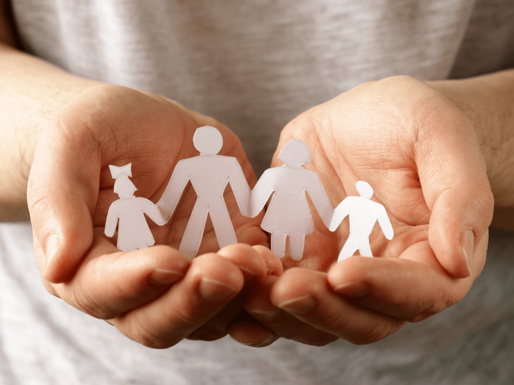 two hands grasping cardboard cutouts of family members