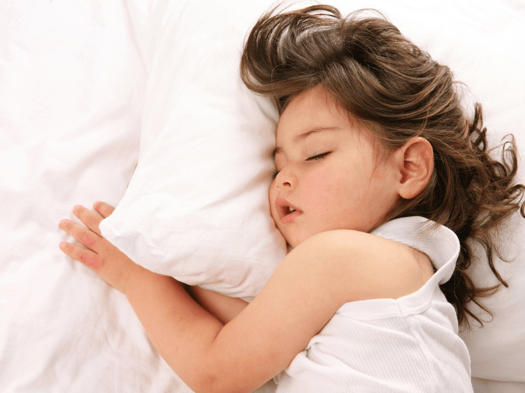 a child fast asleep next to a pillow in bed